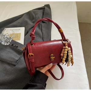 Detail of burgundy vintage crossbody bag with knotted handle and wooden bead tassel