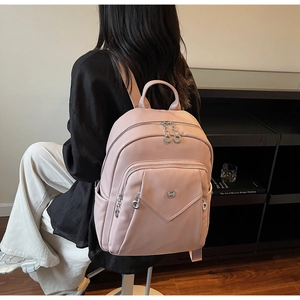 Detailed view of pink leather backpack with metallic logo and functional zip pockets