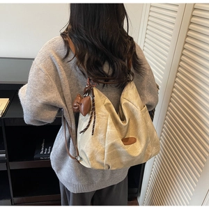 Detail of beige large capacity tote bag with brown bow charm and leather handle