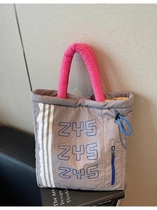 Quilted gray nylon tote bag with pink handles and blue zipper details in a stylish setting