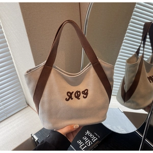 Close-up of large canvas tote bag featuring brown RQS letter embroidery and woven straps