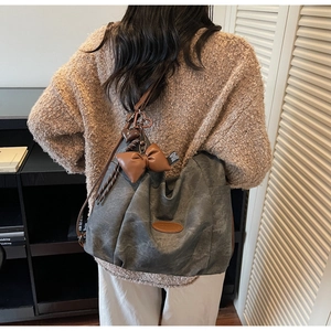 Detail of grey canvas tote bag with brown leather straps and creative heart pendants