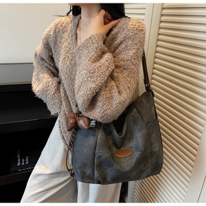 Detail of grey canvas tote bag with brown leather bow charm and adjustable shoulder strap