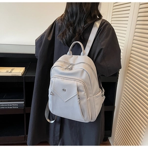 Detail of light gray backpack featuring lychee pattern leather and silver zipper hardware