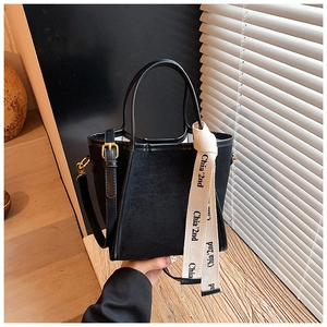 Détail du sac seau noir en daim avec boucles dorées et ruban imprimé Chia'2nd au manche