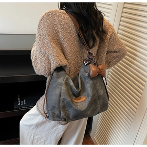 Close-up of large casual tote backpack featuring heart and bow charms in dark grey