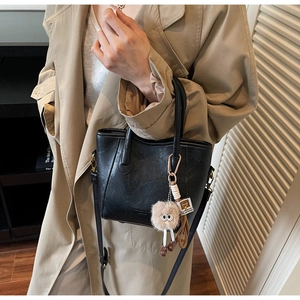 Vista dettagliata della borsa tote nera in pelle con ciondolo peluche e tracolla rimovibile