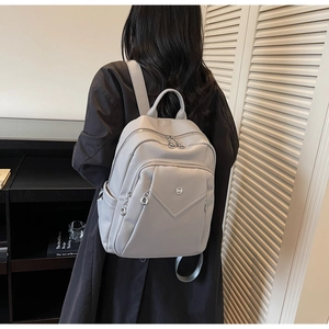 Detailed side view of a light gray lychee grain leather backpack with silver zippers