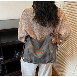 Detail view of large charcoal canvas tote bag with brown leather bow and heart charm