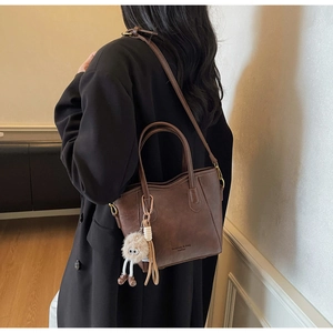 Dettaglio borsa a secchiello vintage in pelle marrone con ciondolo a mostro peloso