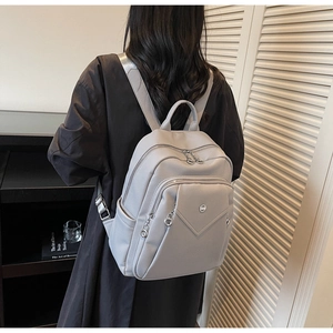 Side view of light grey pebbled leather backpack worn by person in home setting