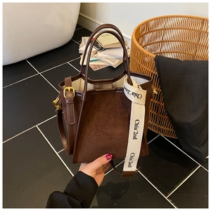 Détail du sac cabas en daim marron foncé avec bordure en cuir et large bandoulière