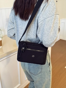 Schwarze Nylon Umhängetasche mit mehreren Reißverschlussfächern und Logo am Modell
