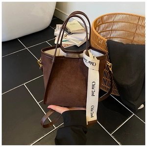 Détail du sac seau en daim marron foncé avec finitions cuir et bandoulière tissée