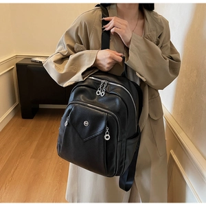 Detail view of stylish black pebbled leather backpack with multiple zipper pockets