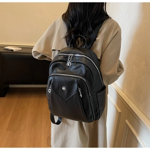 Rear view of a black lychee texture leather backpack worn by a model in a cozy room
