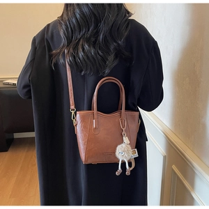 Dettaglio borsa tote marrone caramello con manici in metallo e charm di peluche
