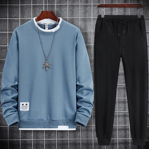 Close-up of fog blue crewneck sweatshirt with layered hem and metallic leaf pendant