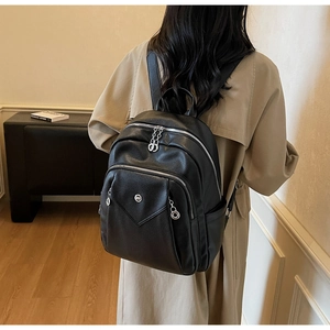 Detail of black pebbled leather backpack showing silver zippers and a chic casual style