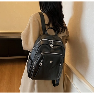 Rear view of model wearing a black pebbled leather backpack with silver zippers