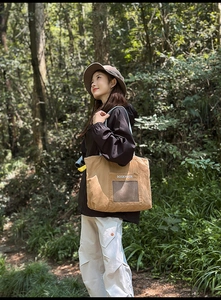 Detail of khaki tote bag with grey mesh pocket showing washed nylon texture in nature