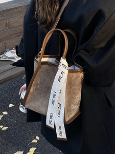 Sac seau rétro en daim marron avec foulard en soie décoratif porté par un mannequin