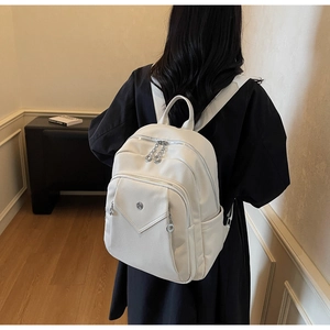 Detail view of white lychee-patterned PU leather backpack showing straps and metal hardware