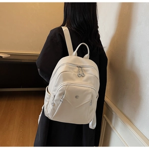 Detail view of cream white backpack with litchi grain texture and silver hardware