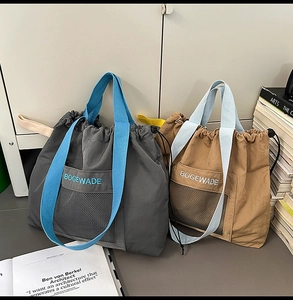 Close-up of drawstring tote bags with vibrant blue handles and front mesh pocket detail