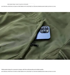 Detail showing deep metal zipper pocket of dark green jacket holding a smartphone