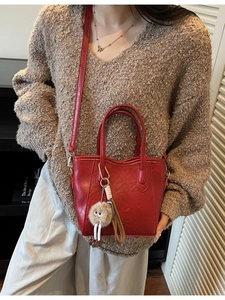 Borsa a secchiello vintage rossa in pelle con ciondolo in peluche su outfit beige casual
