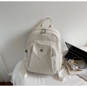 Detail view of cream white pebbled leather backpack with books and office props