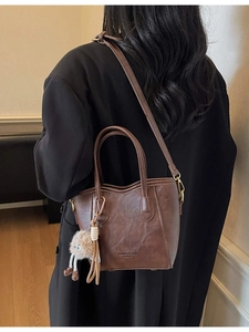 Borsa tote vintage marrone con ciondolo di peluche e tracolla su blazer nero elegante