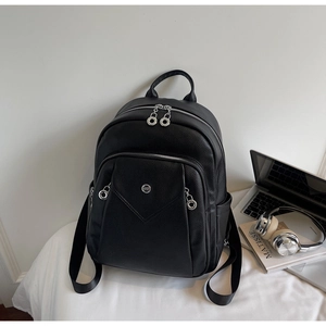 Close-up of black pebble leather backpack with silver zippers and city lifestyle props