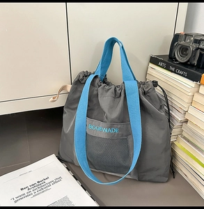 Close-up of minimalist gray nylon tote bag with mesh pocket and blue BOGEWADE embroidery