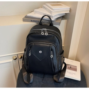 Detail of black lychee grain leather backpack with silver zippers on blue fabric seat