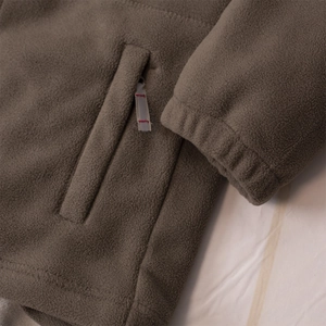 Close-up of brown fleece jacket showing zipper pocket detail and elastic cuffs