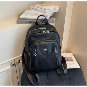 Detail view of the black pebbled leather backpack with triangular front flap and metal logo
