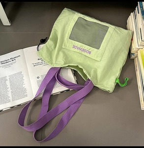 Macro view of bicolor nylon tote bag with purple straps and black mesh pocket detail