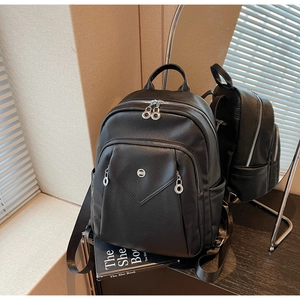 Detail of black pebbled leather backpack showing side structure and silver hardware