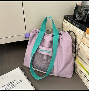 Detail of purple drawstring tote bag featuring green woven handles and mesh pocket