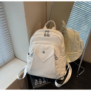 Detail of off-white faux leather backpack with litchi grain texture and front pocket