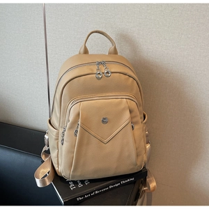 Detailed close-up of beige pebbled leather backpack with silver metal zippers and side pocket