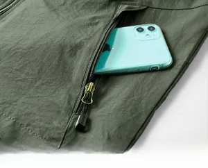 Détail d'un gilet de plein air vert foncé avec poche zippée et rangement pour téléphone