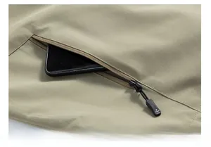 Vue macro de la poche zippée inclinée sur le gilet d'extérieur avec détail mobile