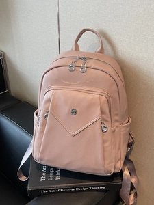 Pink lychee texture faux leather backpack with front envelope pocket on black book