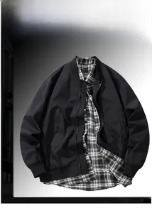 Detail of black workwear jacket collar with size tag and layered plaid shirt