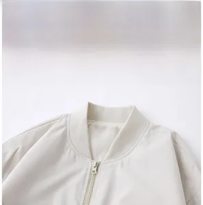 Detail view of the stand-up collar and premium metal zipper on a cream color sports jacket