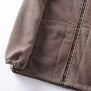 Detail of fleece jacket featuring elastic cuffs, metal zipper, and side pockets in brown