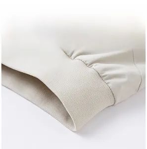 Close-up of the beige windbreaker jacket hem showing premium ribbed stitching and fabric texture